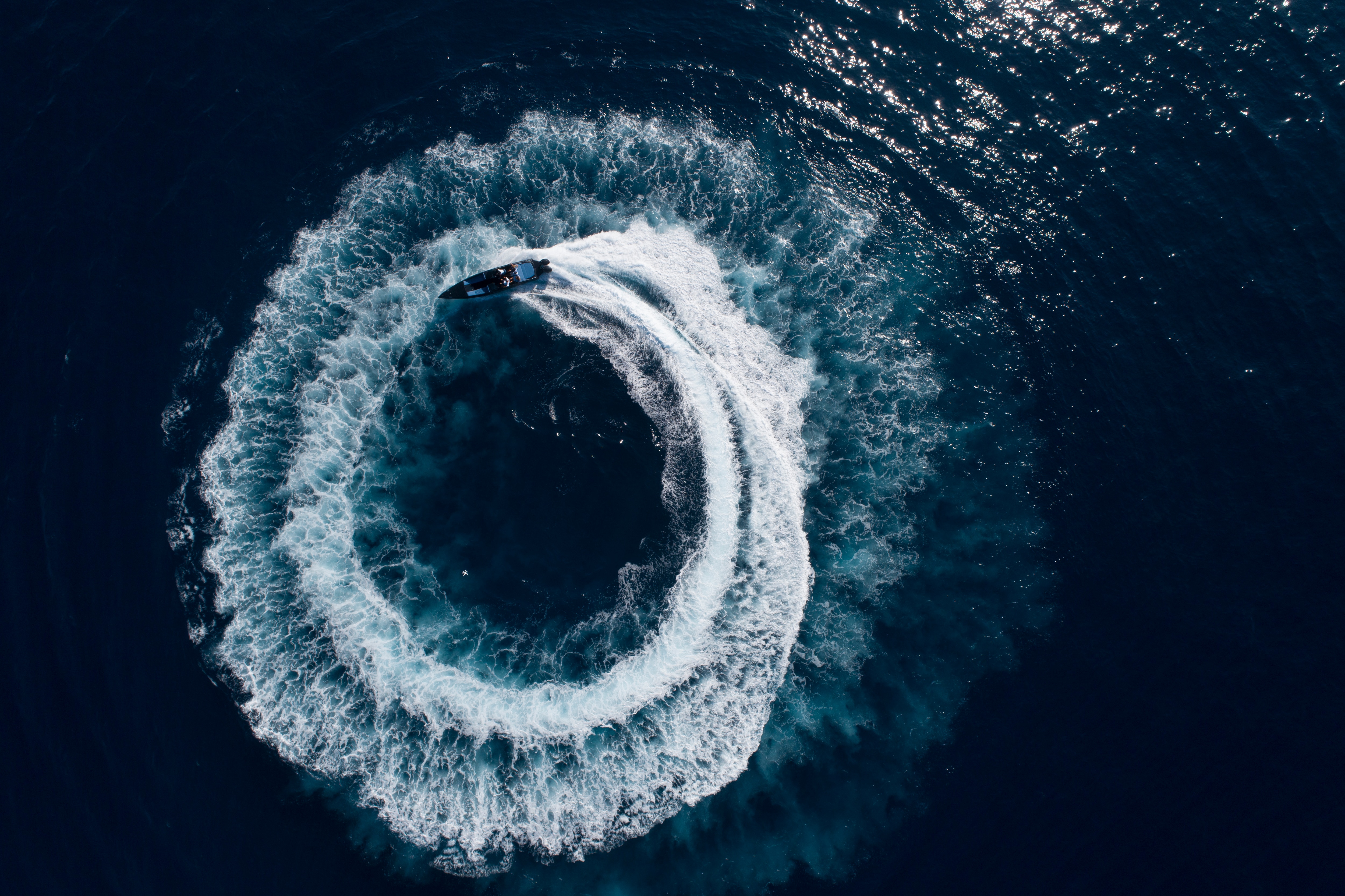 Bird view of a boat doing large circles in the watter