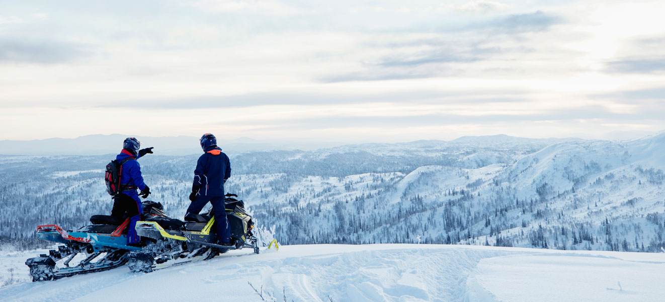 Two men sitting on their Lynx Snowmobile and looking at the horizon