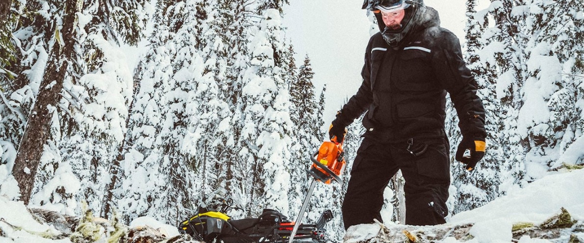 Človek, ki je v bližini svoje ekspedicije Ski-Doo nosil motorno žago