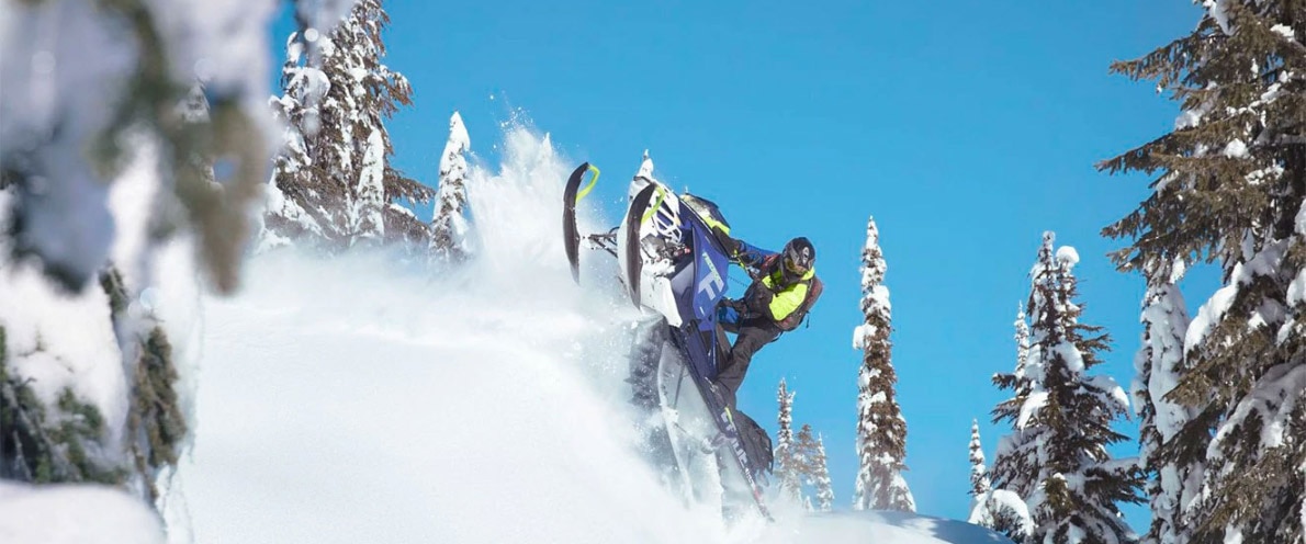 Man jumping high while riding a Freeride snowmobile