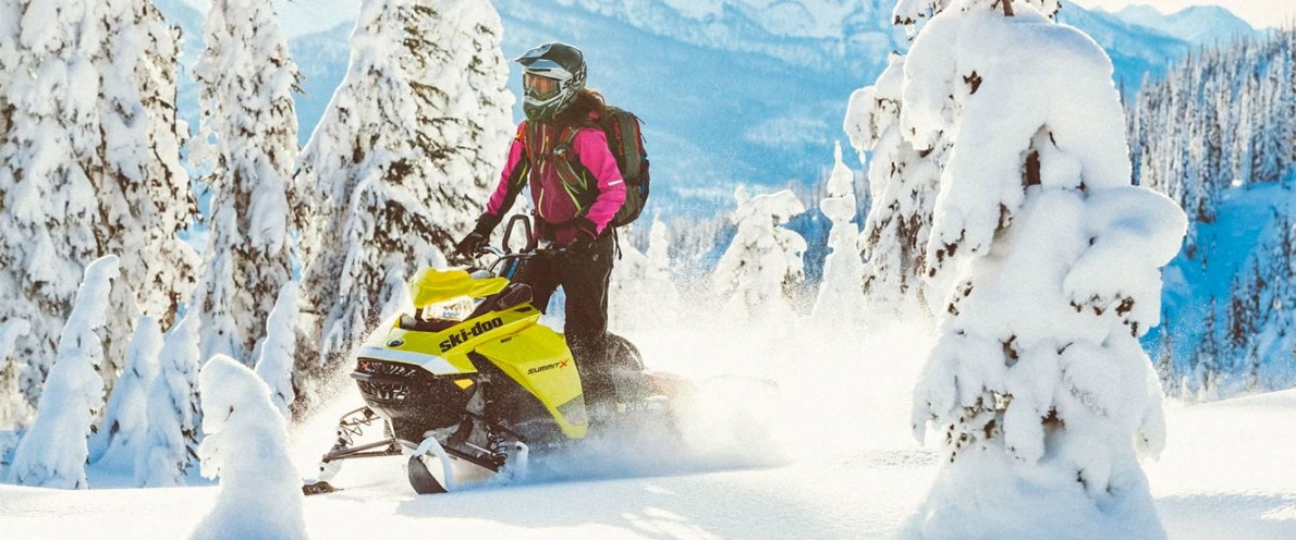 Žena stojící za jízdy na sněžném skútru Ski-Doo Summit