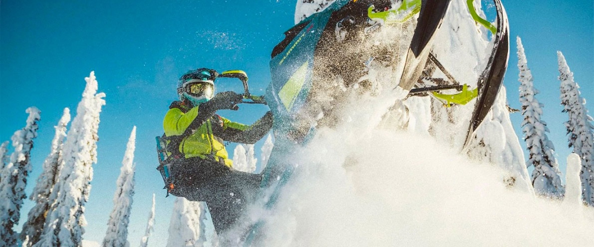 Blízký záběr muže letícího vzduchem se svým sněžným skútrem Ski-Doo Summit