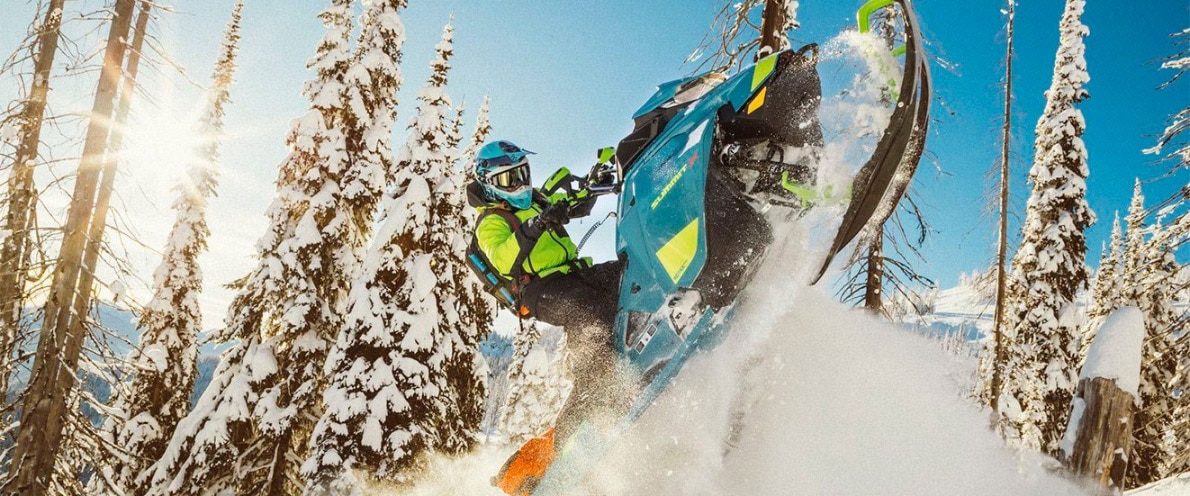 Širokoúhlý záběr muže letícího vzduchem se svým sněžným skútrem Ski-Doo Summit