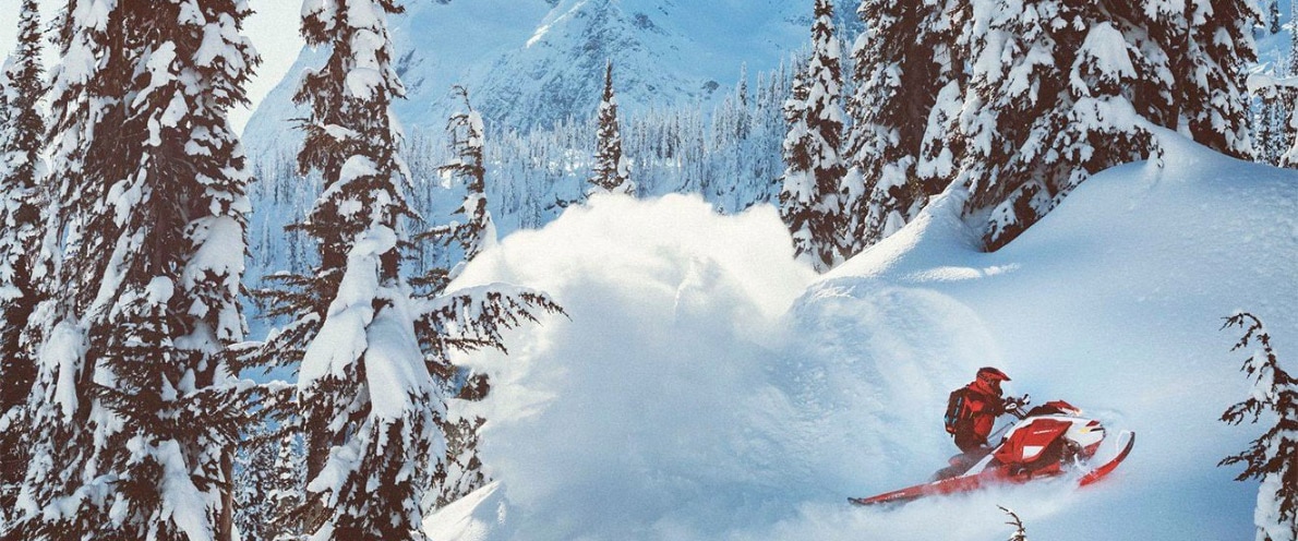  Človek, ki pluje v snegu s svojimi motornimi sanmi na vrhu