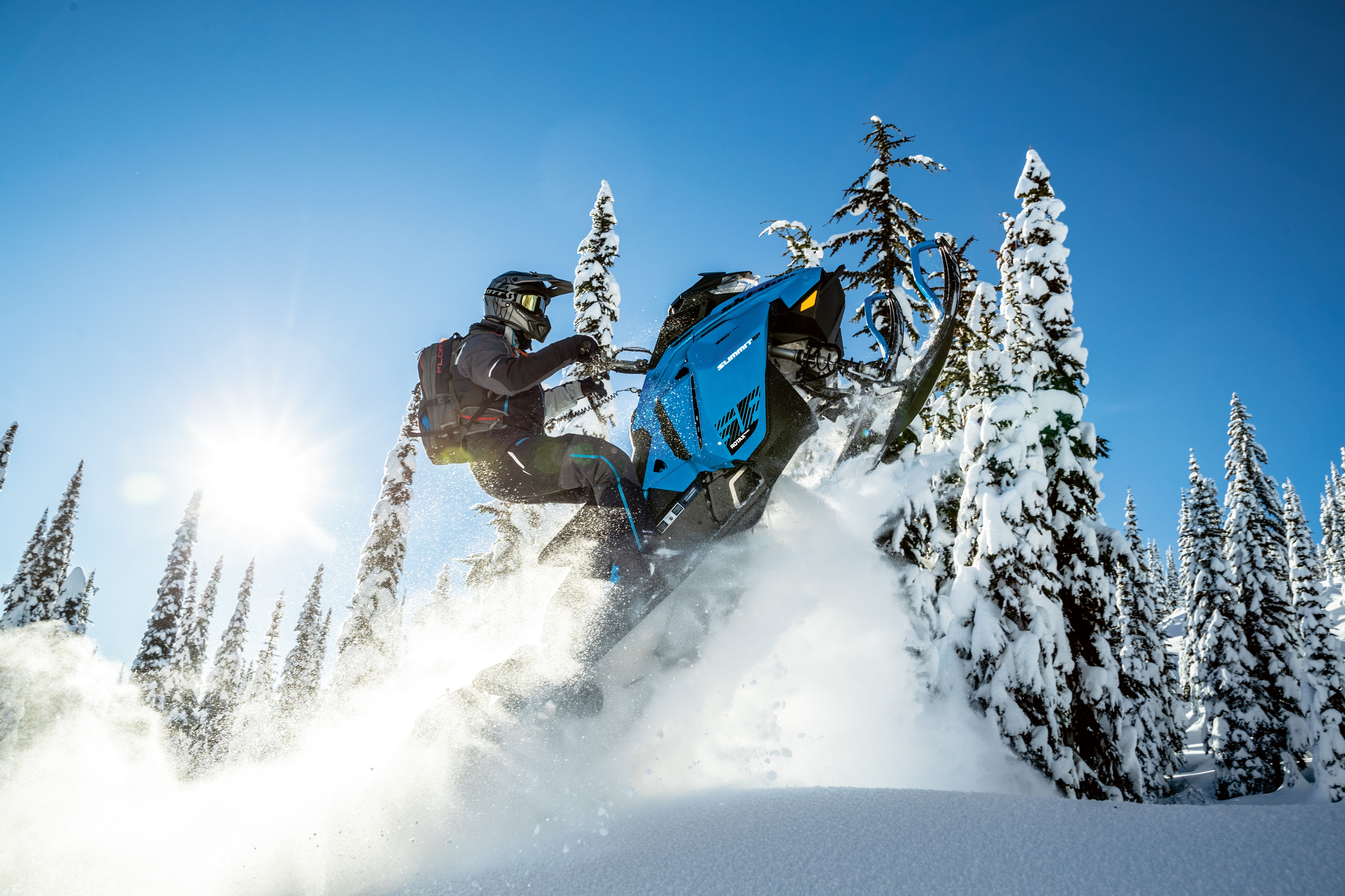 Muž letící vzduchem se svým sněžným skútrem Ski-Doo Summit