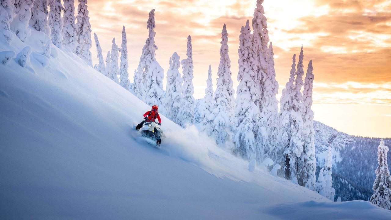 Muž jazdí na Ski-Doo Summit bokom kopca