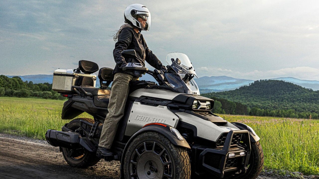 A woman standing on a Can-Am Canyon 3-wheel motorcycle