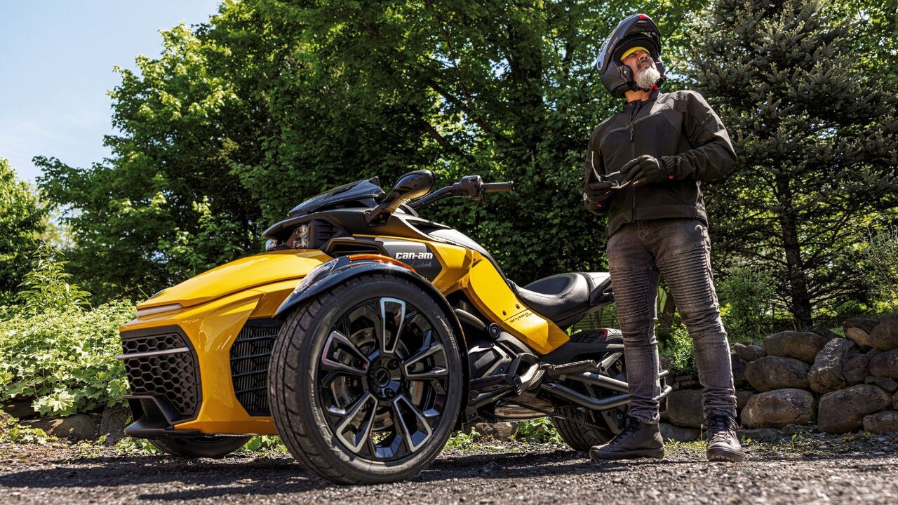 A rider standing next to a 2026 Can-Am Spyder F3 3-wheel motorcycle