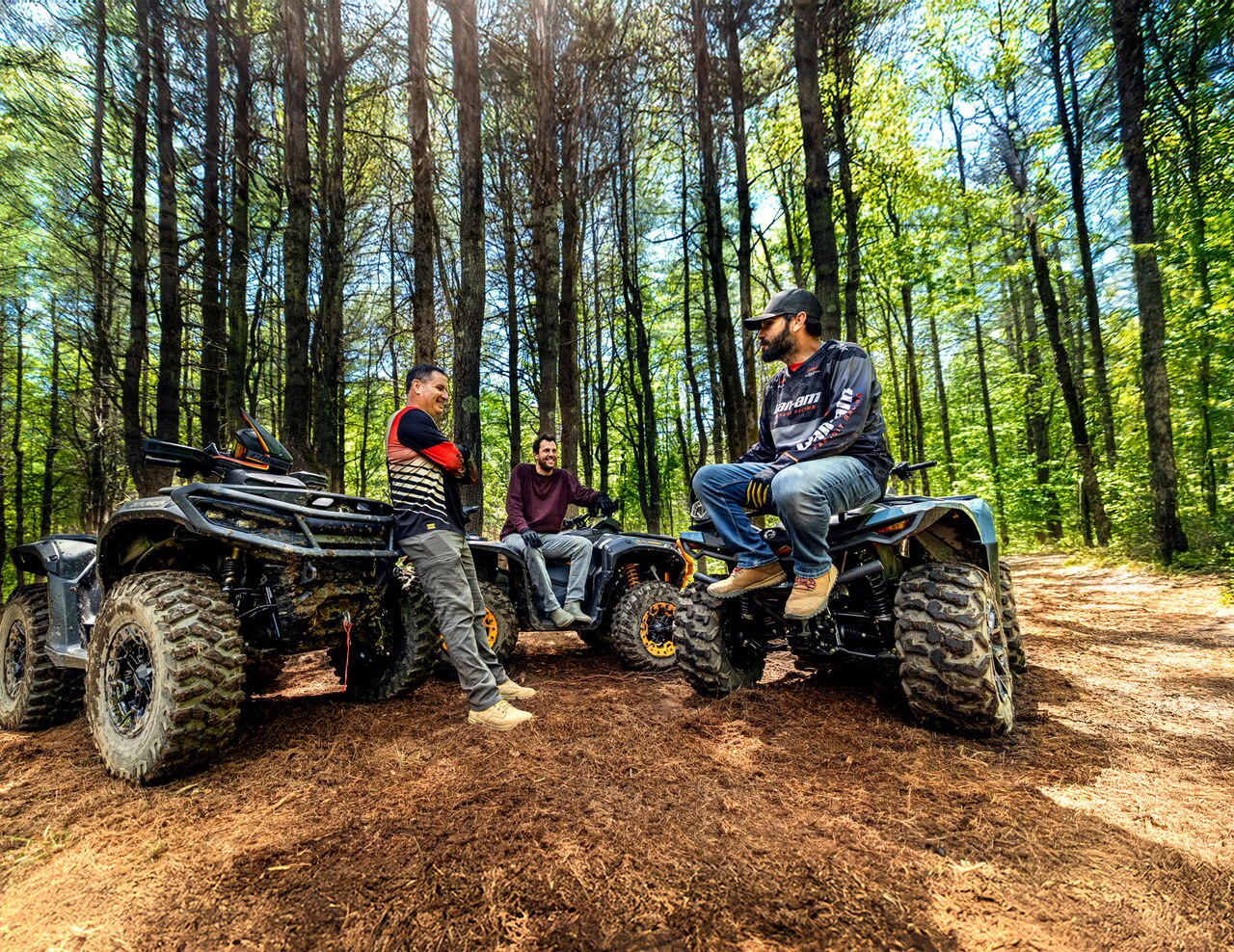 عدد من السائقين يأخذون قسطًا من الراحة على متن دراجات 2026 Can-Am Outlander في الغابة