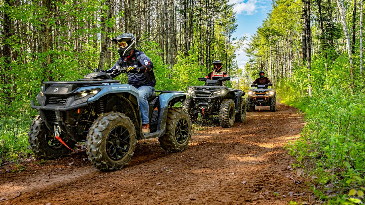 Several Can-Am Outlander ATVs following each other on a trail