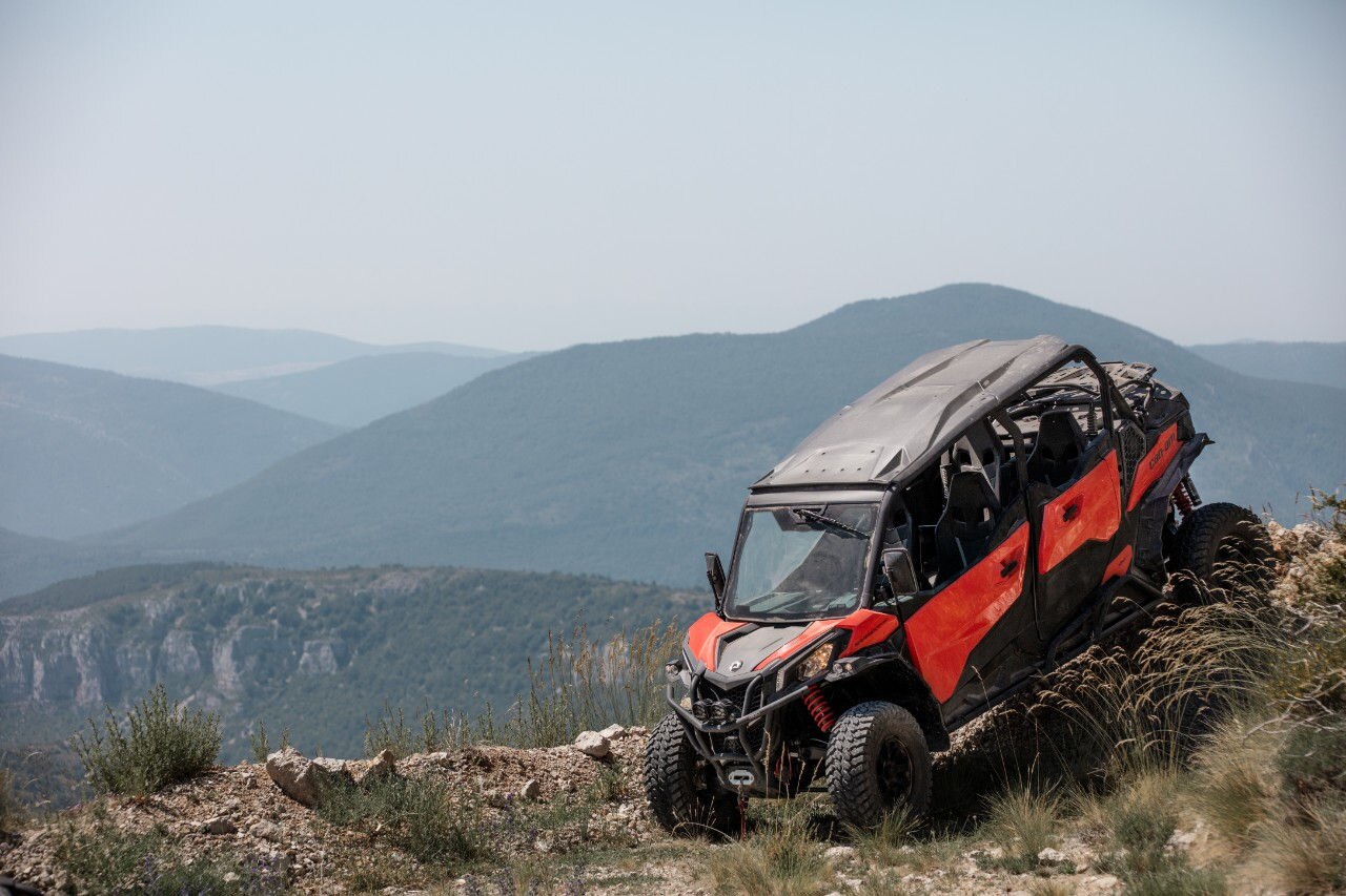 Can-Am Maverick Sport MAX driving down a steep hill in front of a mountainous background