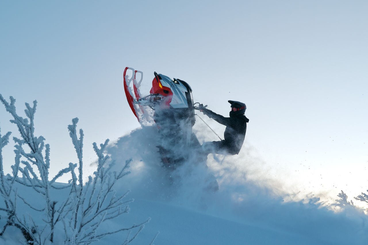 Rider jumping out of deep snow on a 2027 Lynx Shredder RE