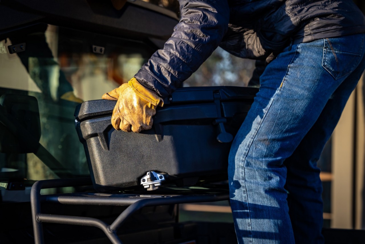 En arbejder med handsker installerer en LinQ Cargo-boks i ladet på sin Defender Lonestar CAB