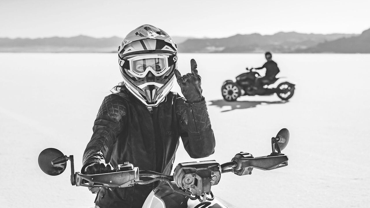 Frau sitzt auf ihrem Fahrzeug und hebt die Hand