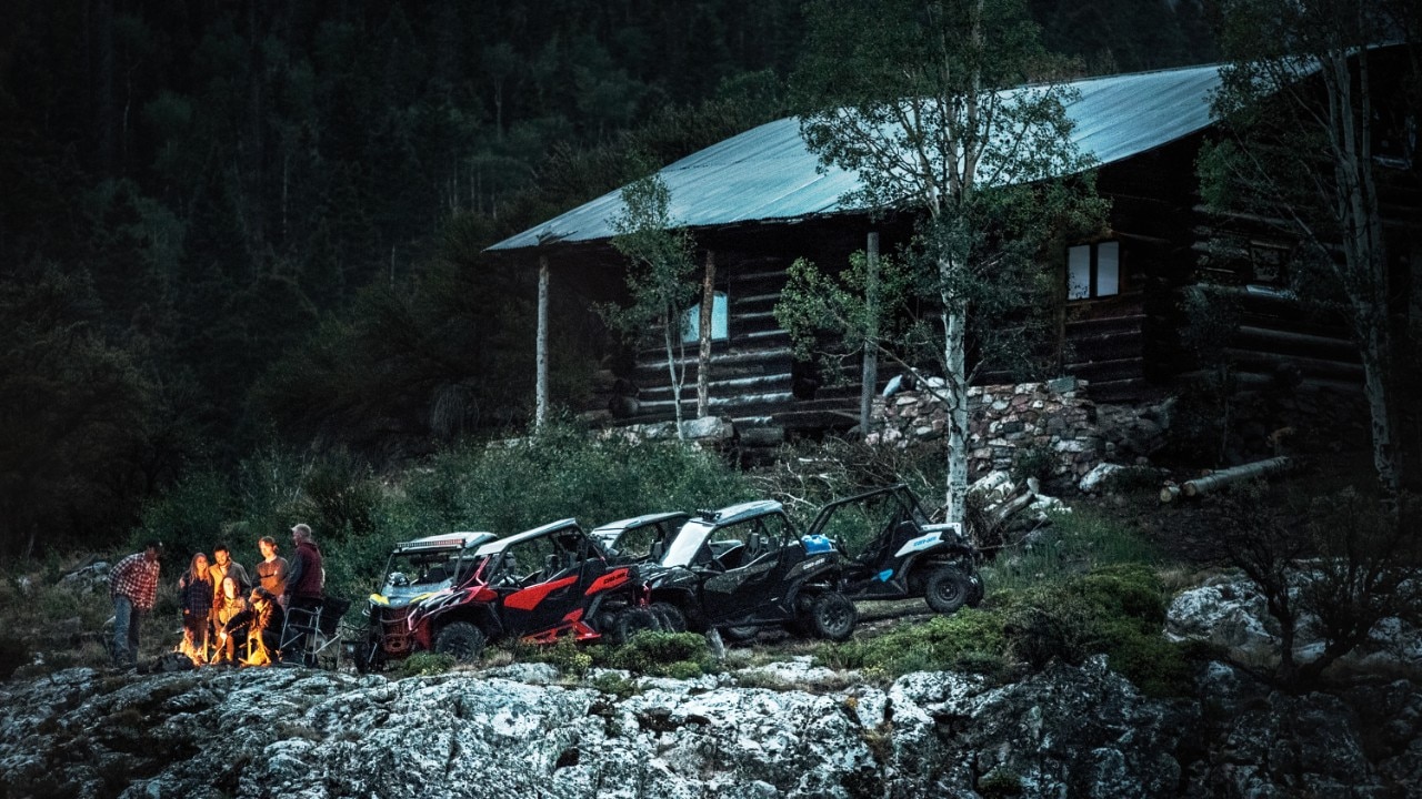 Freunde in der Nähe ihrer Maverick Trail-Modelle in der Nähe einer Hütte im Wald