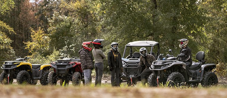Group of riders next to Can-Am Outlander and Can-Am Defender