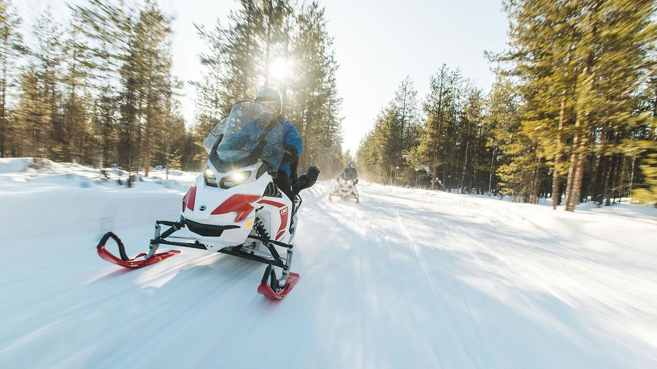 Two Lynx Adventure Electric snowmobiles riding on flat trail