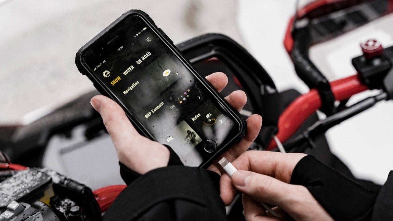 BRP GO! app on a phone near a Lynx snowmobile