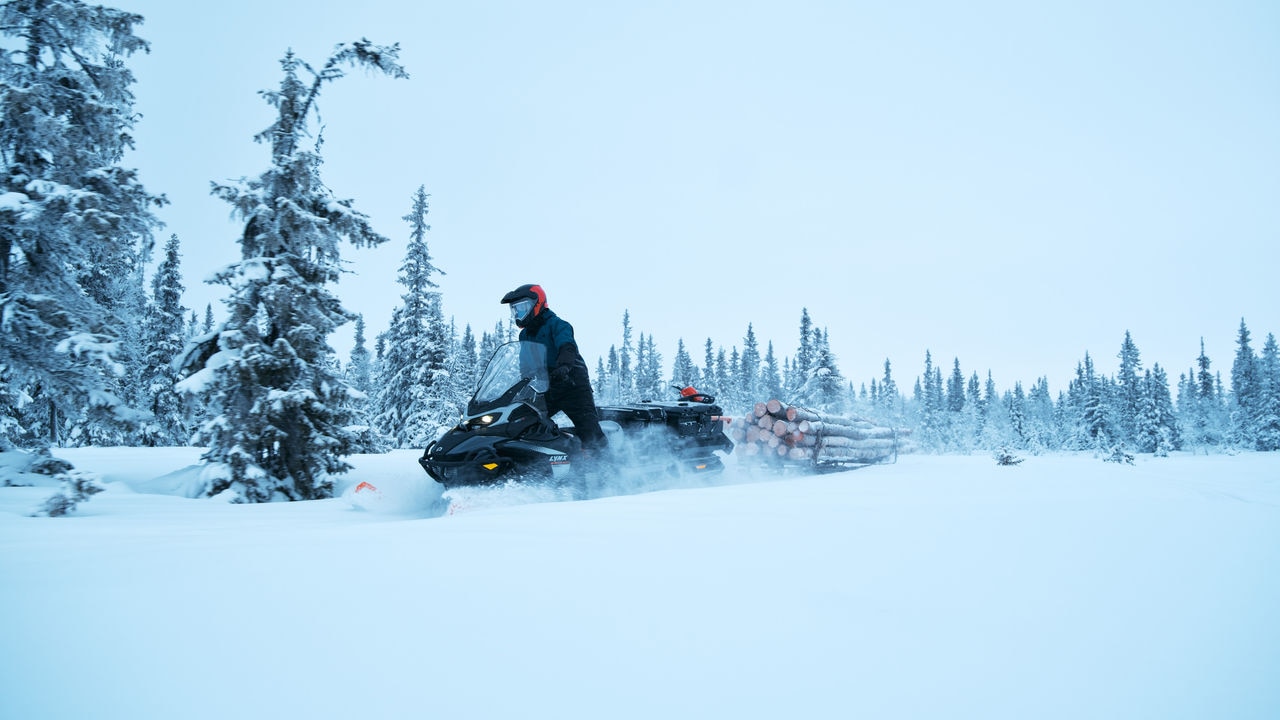 Rider pulling logs with a 2027 Lynx 69 Ranger PRO snowmobile