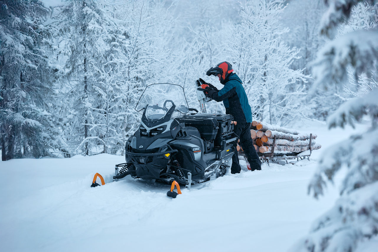 Rider storing a chainsaw on his 2027 Lynx 69 Ranger PRO snowmobile