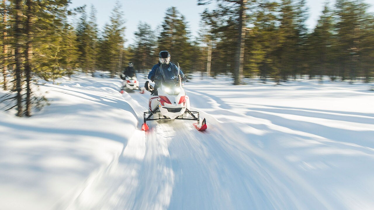 Two Lynx Adventure Electric snowmobiles riding on trail