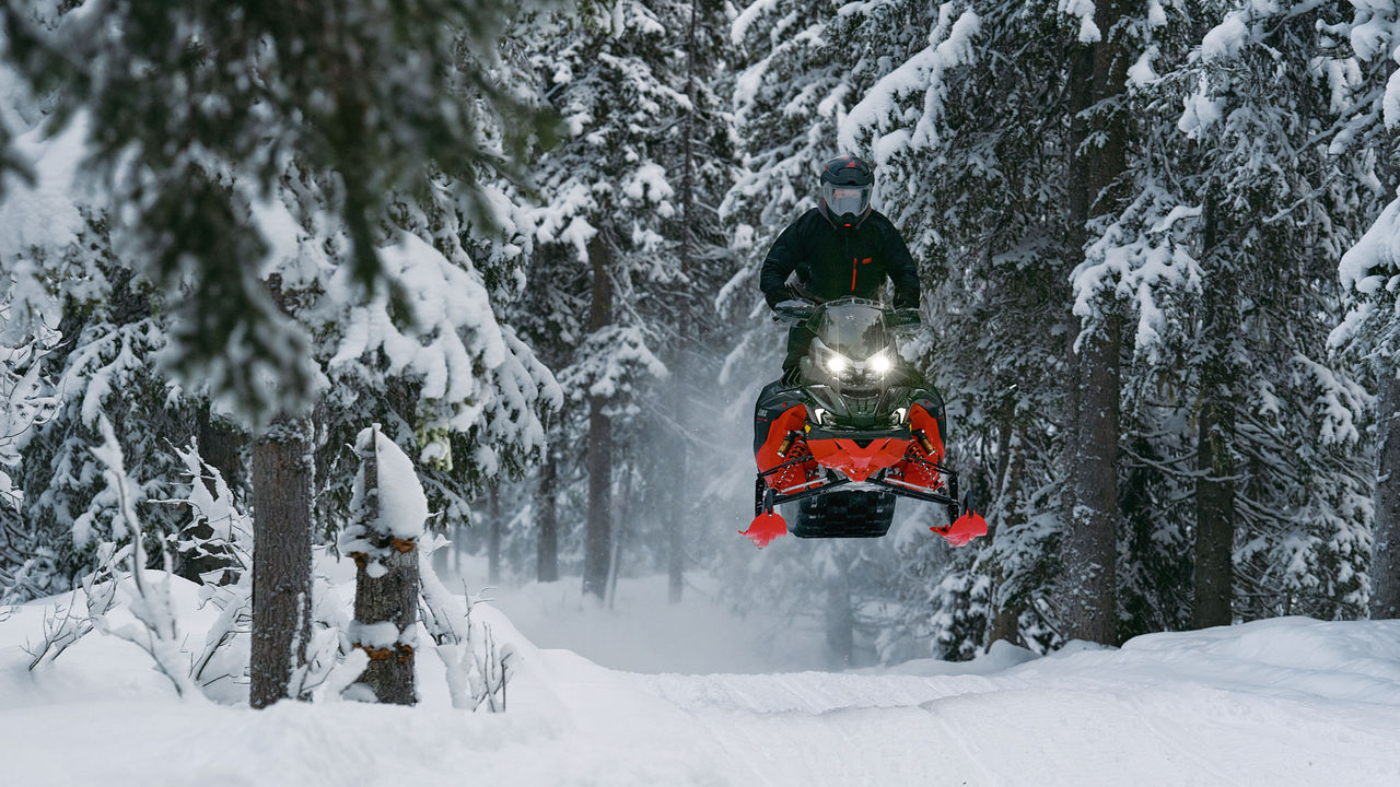 2026 Lynx Brutal RE snowmobile leaping over a bump on the trail.