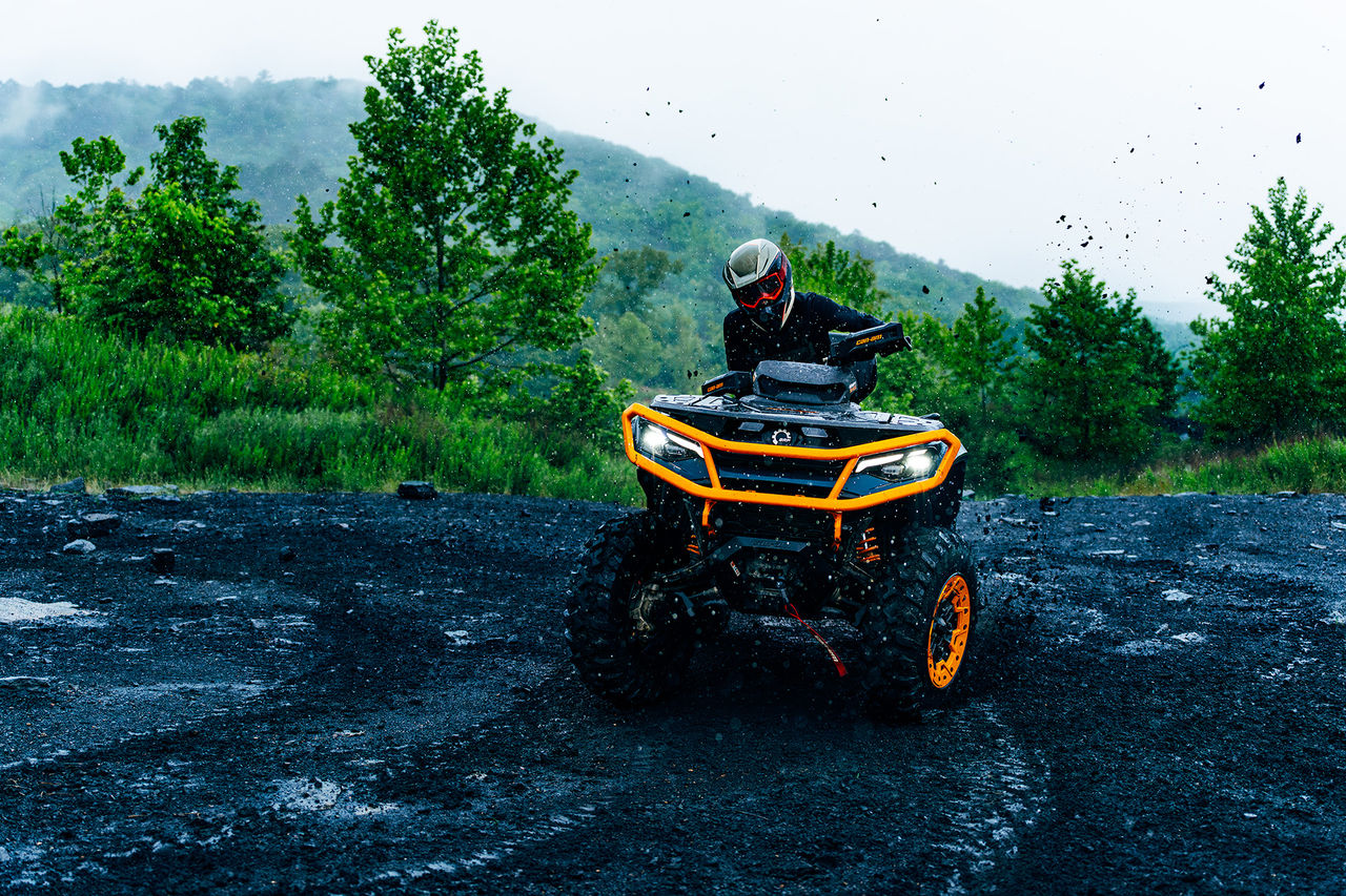 2027 Can-Am Outlander ATV riding on a black mud puddle