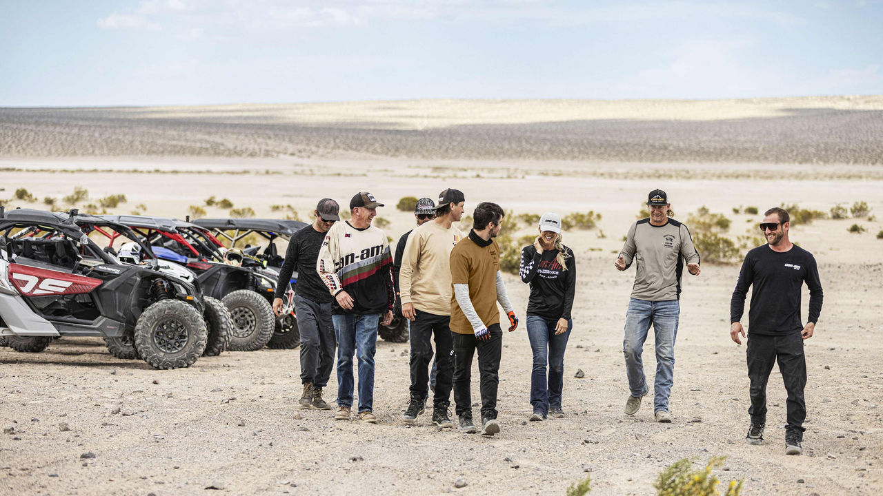 Can-Am Off-Road Ambassador Dustin Jones and friends walking in the desert near their Maverick vehicles