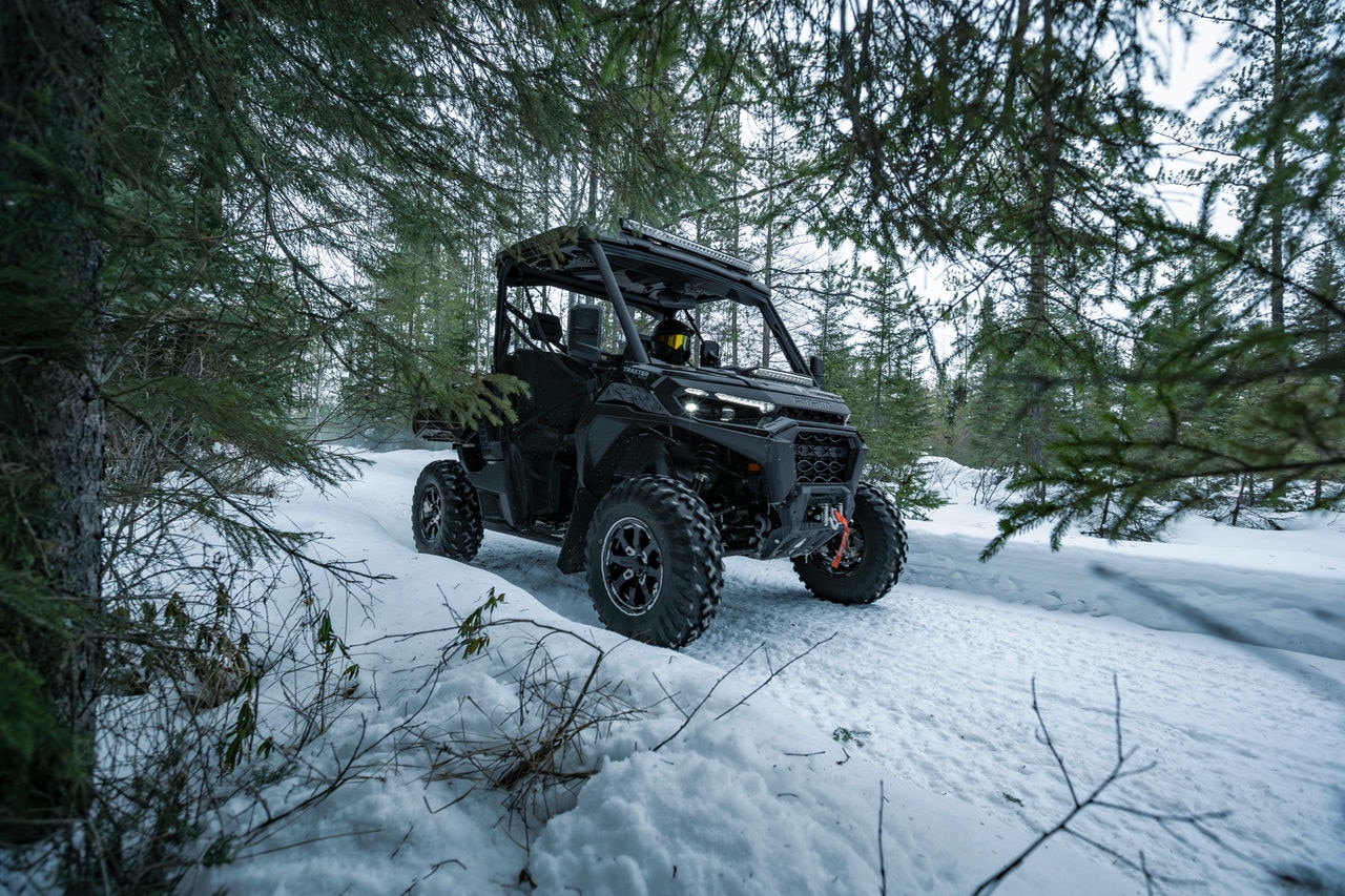 A Can-Am Traxter XU HD1 riding through a snowy trail