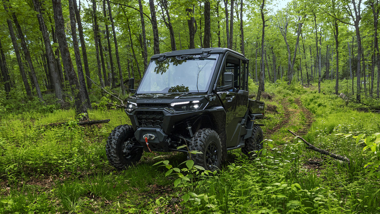 Can-Am Traxter XU SxS riding on a muddy trail through a forest