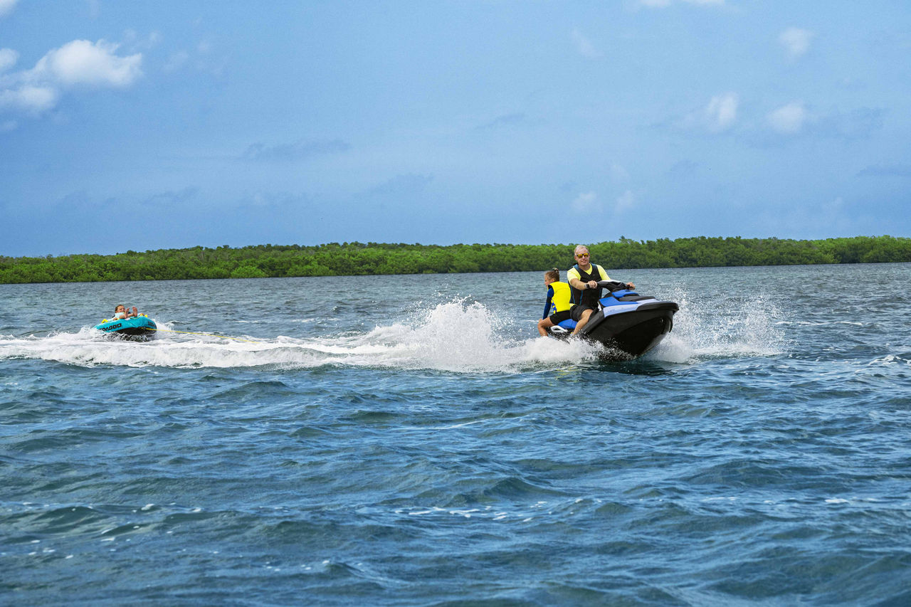 Dad and daughter on a Sea-Doo Spark 3UP personal watercraft pulling a tube
