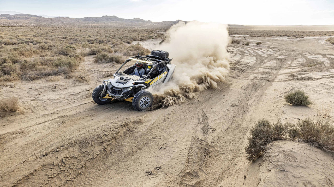 Can-Am Maverick R riding in the desert leaving a trail of dust behind