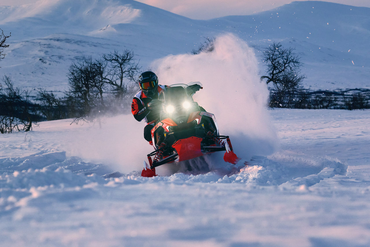 Man riding a 2027 Lynx Rave RE 3500 snowmobile on a snowy field