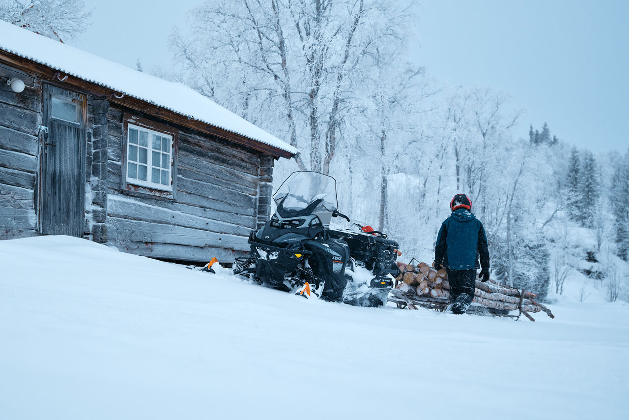 Idle 2027 Lynx 69 Ranger PRO while rider walks towards the logs
