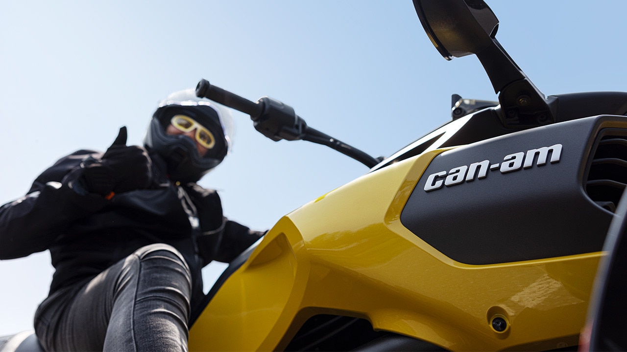 Un pilote fait un pouce levé sur son Can-Am 3 roues 2026 jaune.