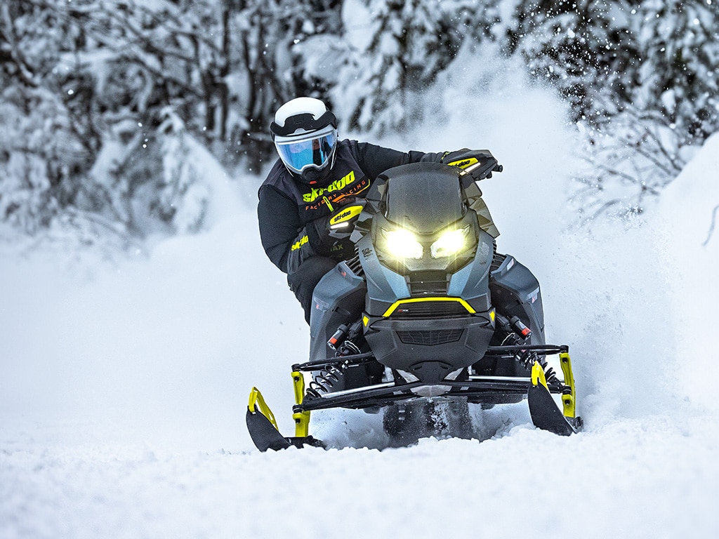 Un pilote roulant sur une Ski-Doo Renegade X-RS 900 ACE Turbo dans une forêt enneigée