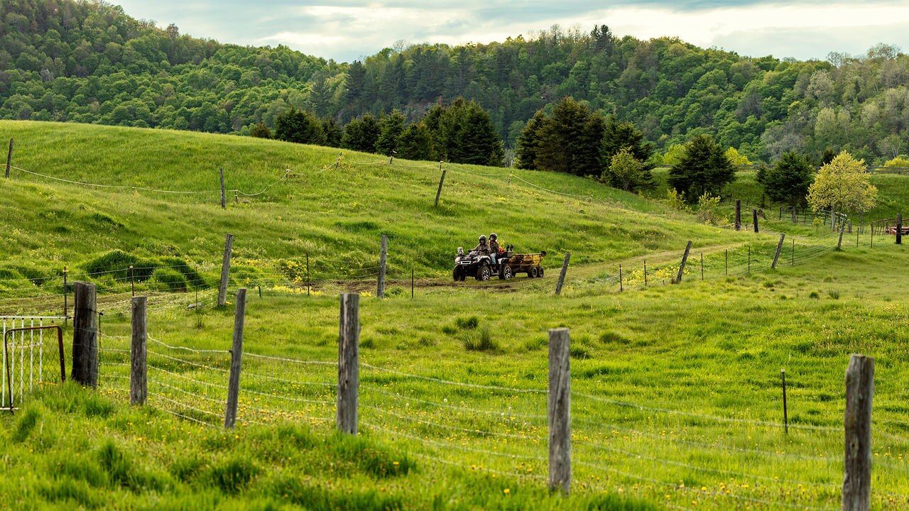 A 2026 Can-Am Outlander Electric pulling load on a farm