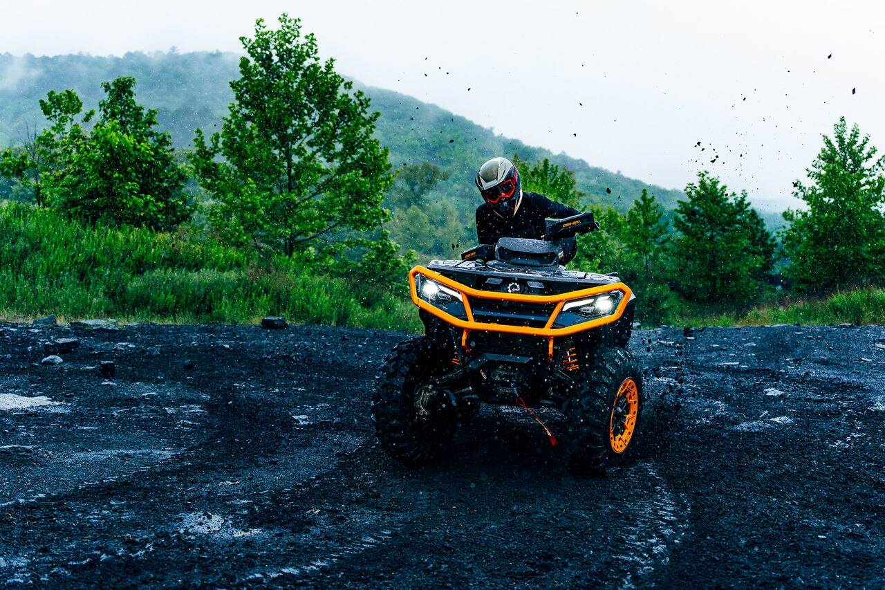 2027 Can-Am Outlander ATV riding on a black mud puddle