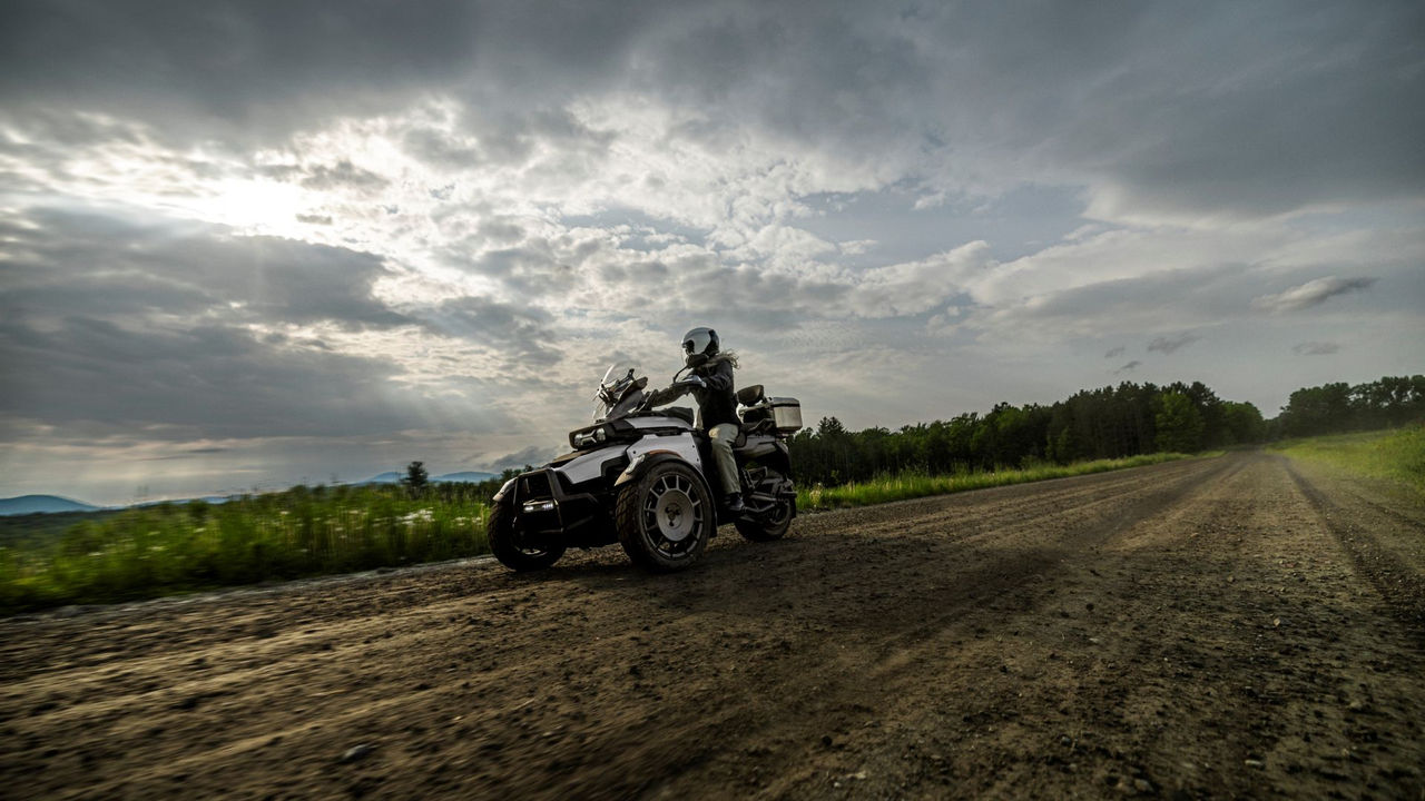 Une motarde au guidon d’une moto Can-Am Canyon 3-roues 2026 sur une piste de terre.