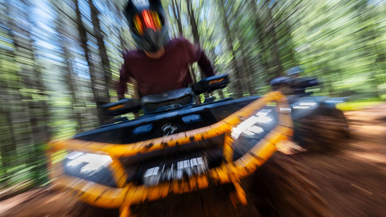 Two 2026 Can-Am Outlander ATV riding through a forest