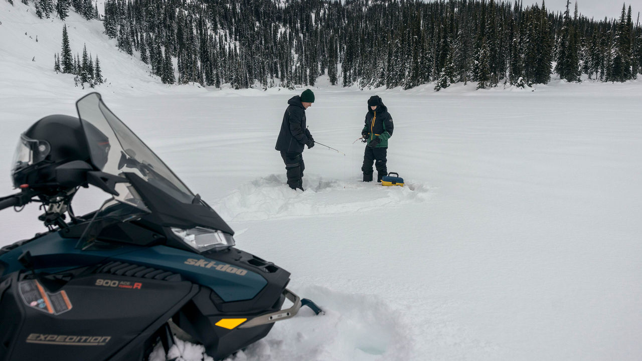 Dva vozača motornih sanjki pecaju u blizini Ski-Doo Crossover Expedition