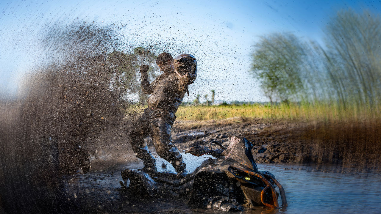 Man standing on his muddy Can-Am ATV