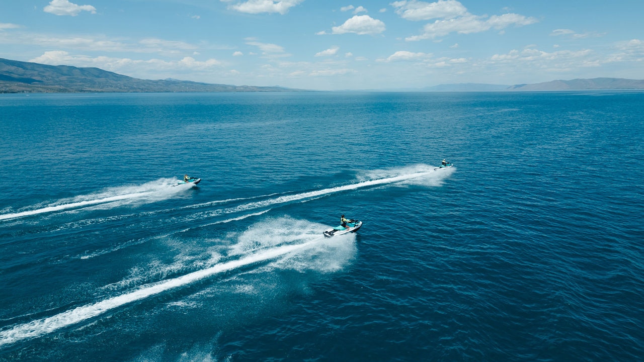 Three Sea-Doo personal watercrafts riding at high speed