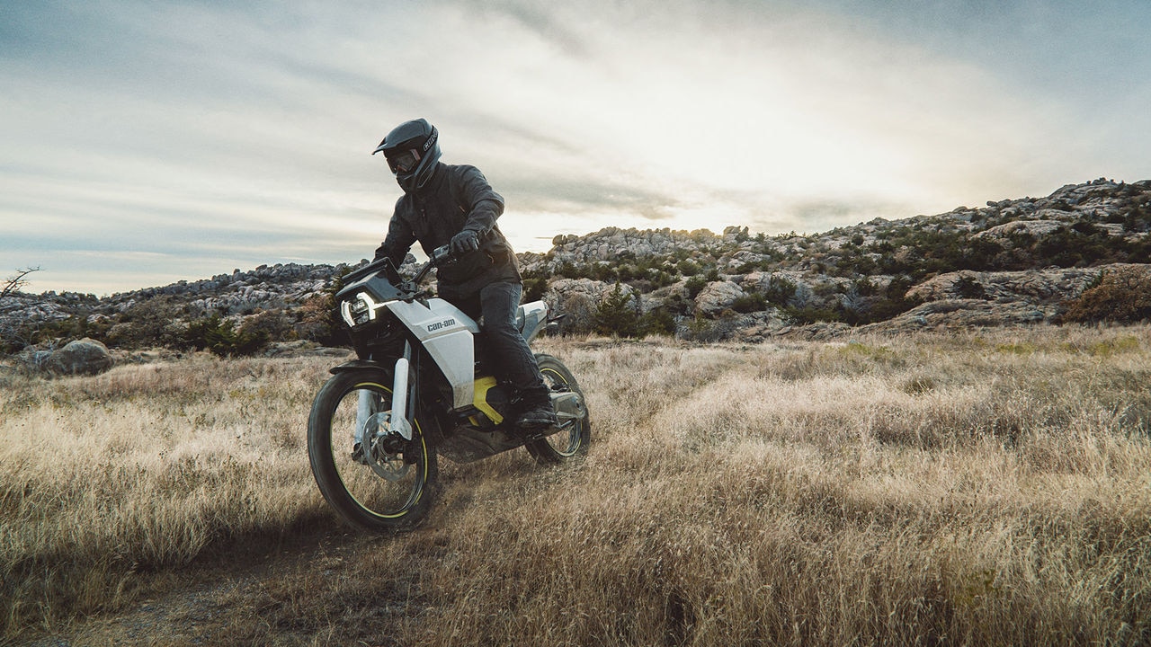 Man riding a Can-Am Origin Electric motorcycle in a field