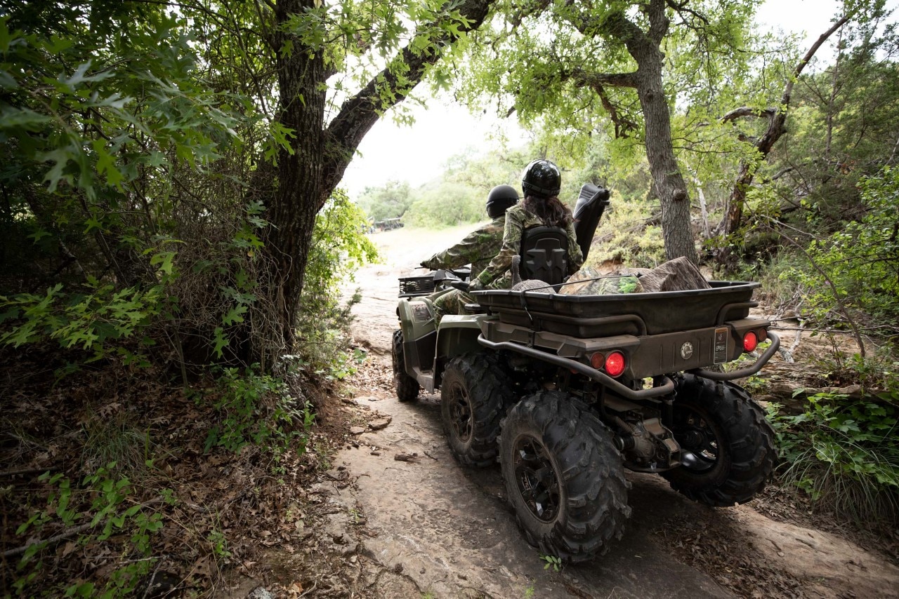 Two people on a Can-Am Outlander MAX 6x6 DPS ATV filled with hunting gear