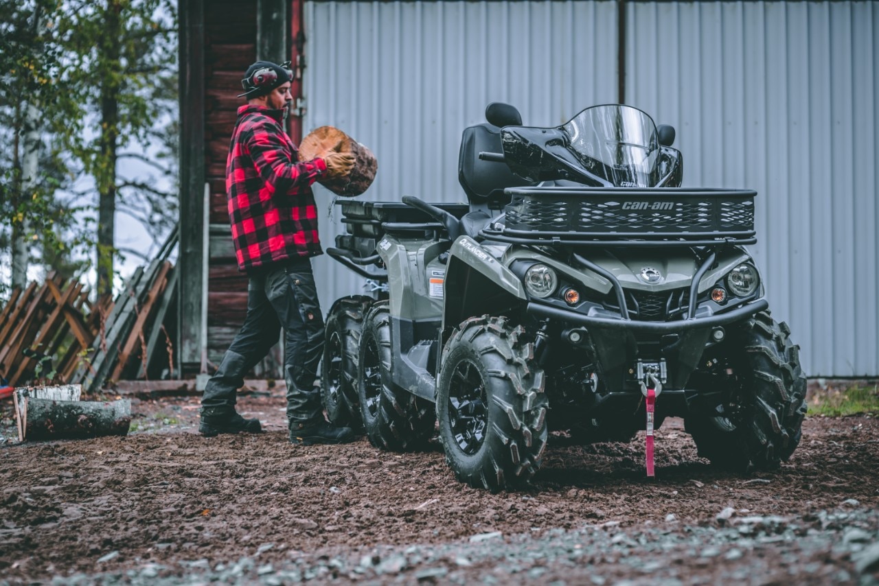A man putting wood in a basket in the back of his Can-Am Outlander 6x6 ATV