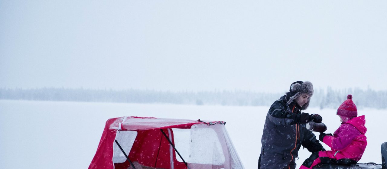 A man and a woman are installing a little girl in the back of a 2021 Lynx 59 Ranger Model which is equipped with a rear trailer.