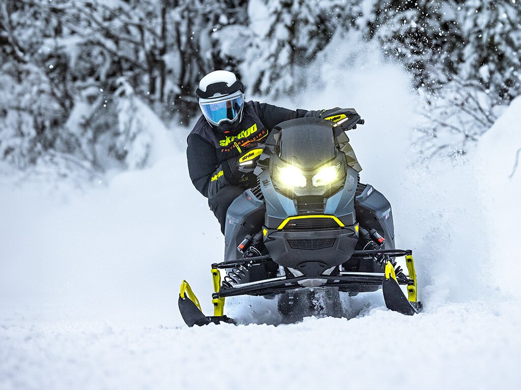 Rider riding a Ski-Doo Renegade X-RS 900 ACE Turbo in a snow-filled forest