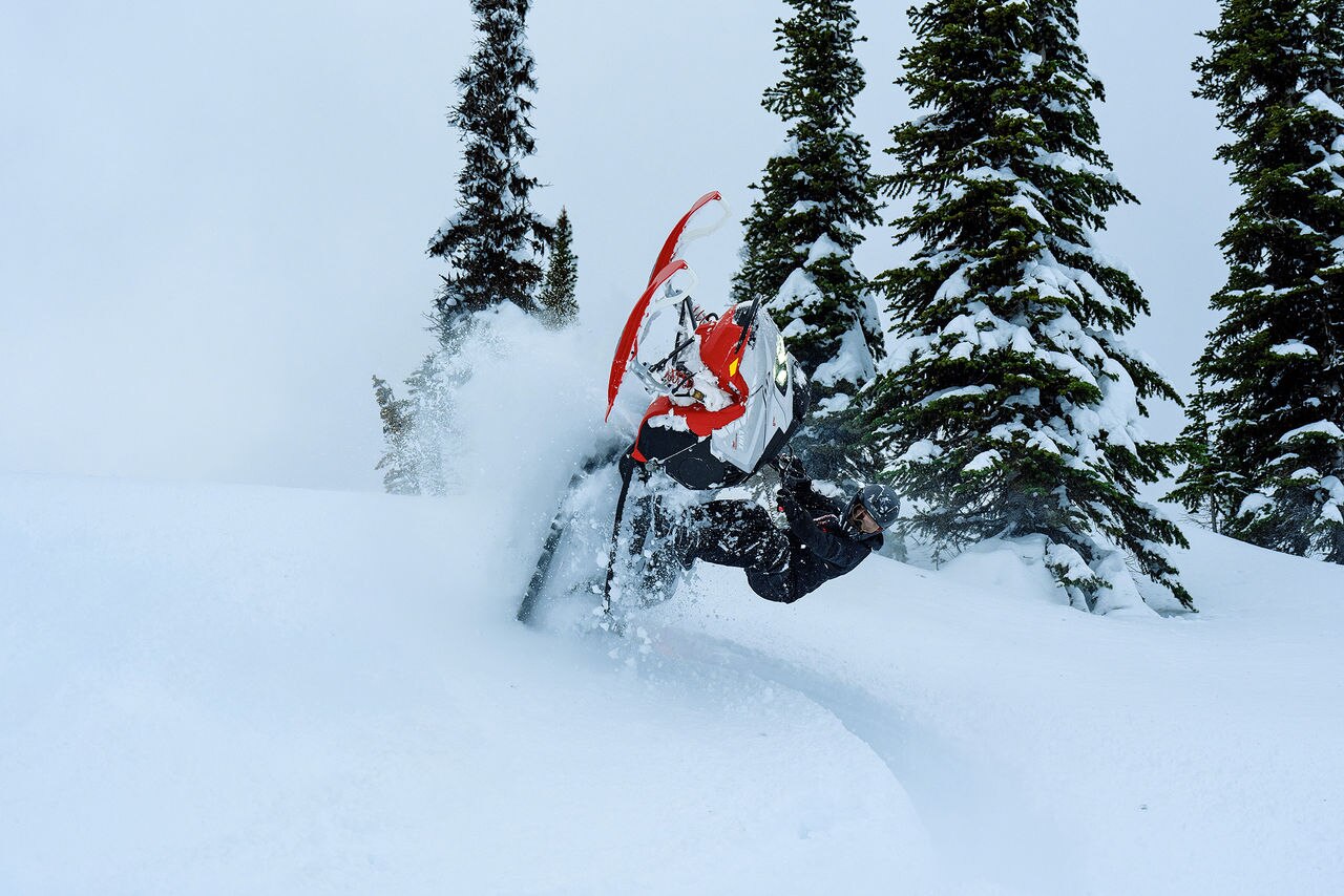 Rider performing a stunt with a 2027 Lynx Shredder RE snowmobile in deep snow