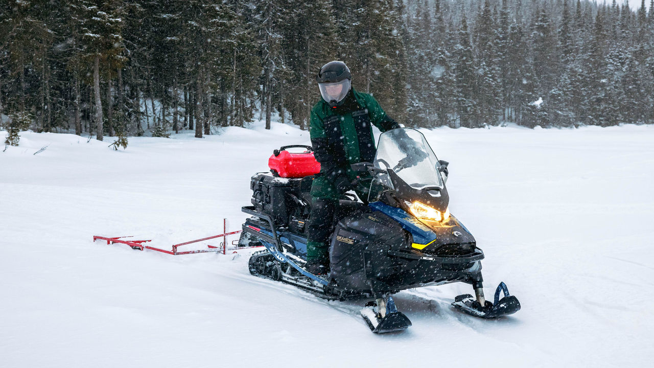 Човек што влече санка на својот Ski-Doo Skandic од 2025 година